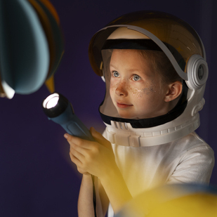 a child in an astronaut helmet holds a flashlight exploring a colorful space-themed environment