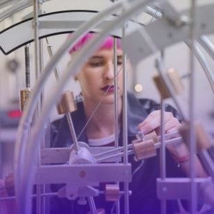 a person carefully adjusting components of a machinery setup with metal rods and wheels