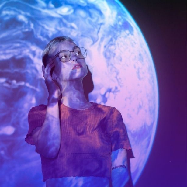 a person stands in front of a blue planet projected onto a wall