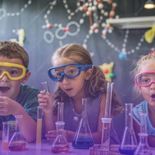 children interact with a science exhibit experimenting with various materials