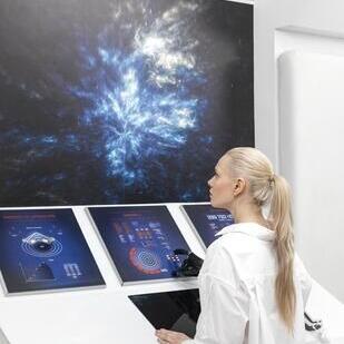 a person interacts with futuristic touchscreen displays surrounded by a cosmic-themed backdrop